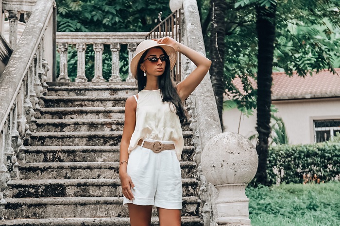 picture of a girl on an outdoor stairs of a house wearing white summer outfit with accessories 