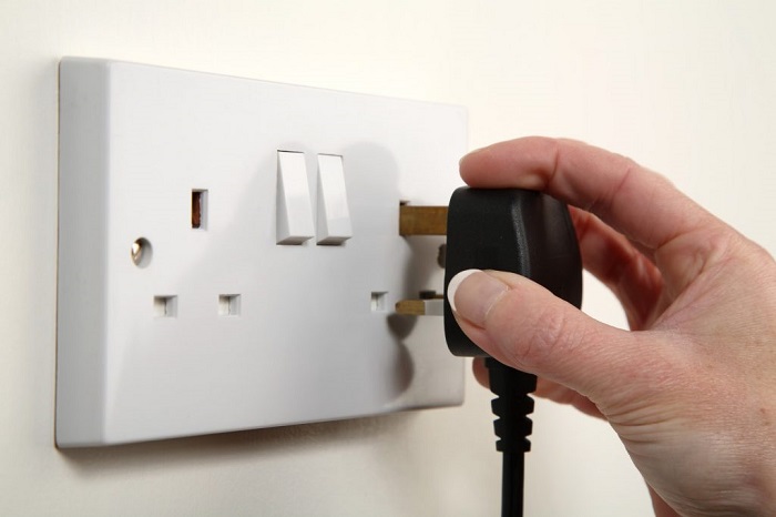 man plugging in a plug into a power point