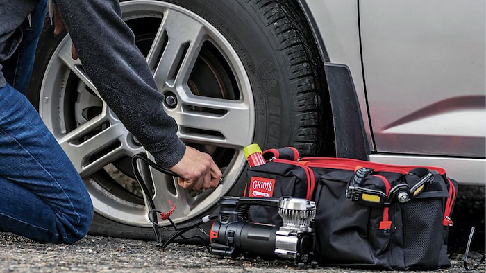 man working on his flat tyre with roadside emergency kit