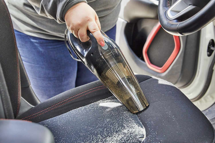 woman cleaning his car seat with a vacuum cleaner