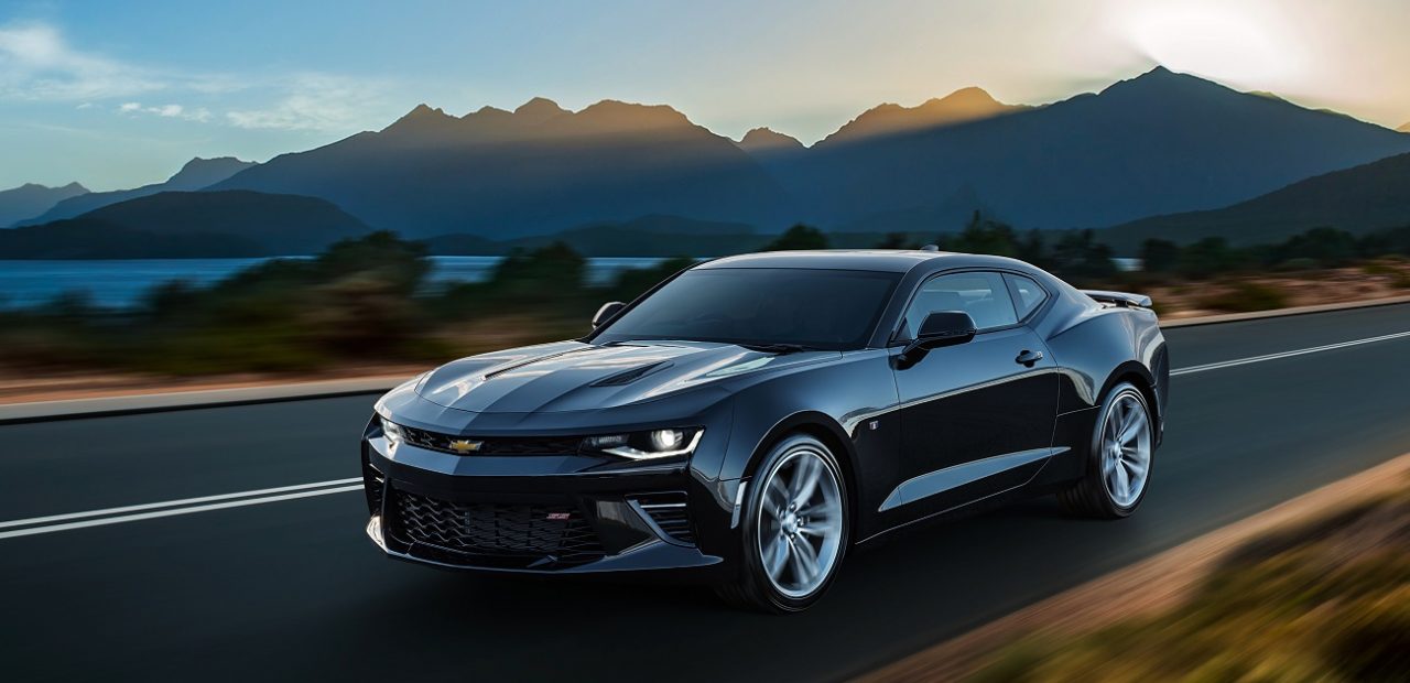 picture of a new car driving beside a lake and mountains