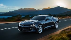 picture of a new car driving beside a lake and mountains