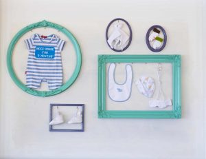 picture of baby's stuff in a blue frames on the wall