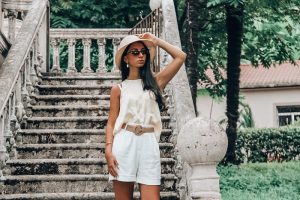 picture of a girl on an outdoor stairs of a house wearing white summer outfit with accessories