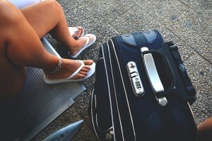 picture of women in flip flop beside a travel bag