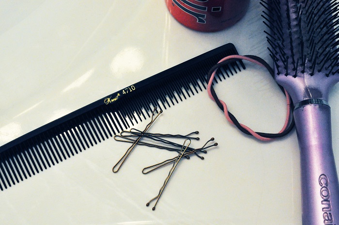 picture of hairbrush, hair ties, pins and Hair spray on a white surface
