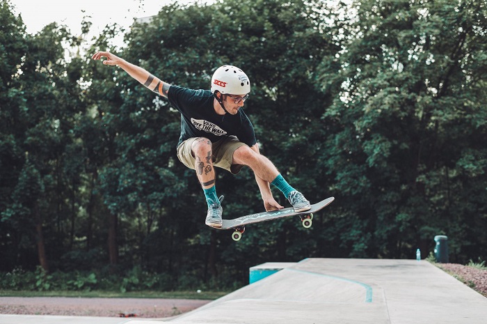 picture of a man skateboarding in a park wearing helmet 