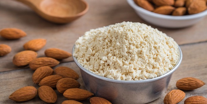 almond flour in bowl and almonds on table 