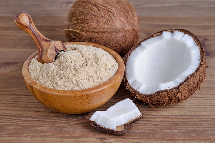 coconuts and coconut flour in wooden bowl on table