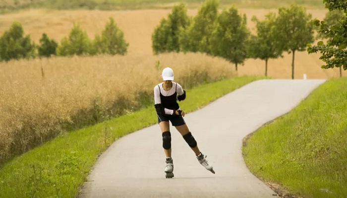 picture of a person riding roller skates wearing protective gear on a path in nature 