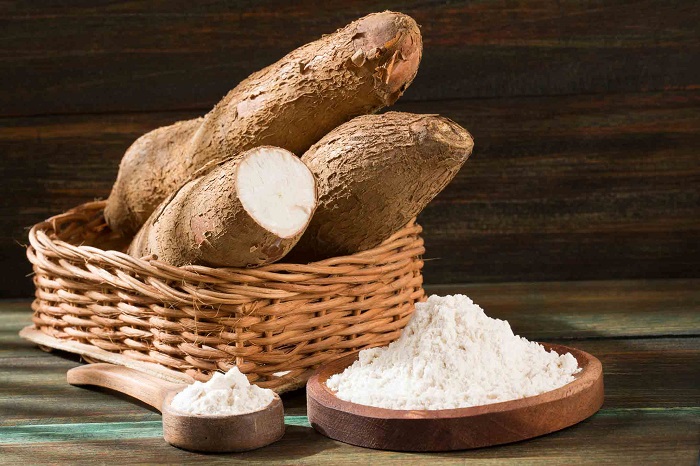 cassava roots and cassava flour in bowl on table