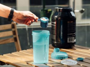 man putting whey protein powder in shaker