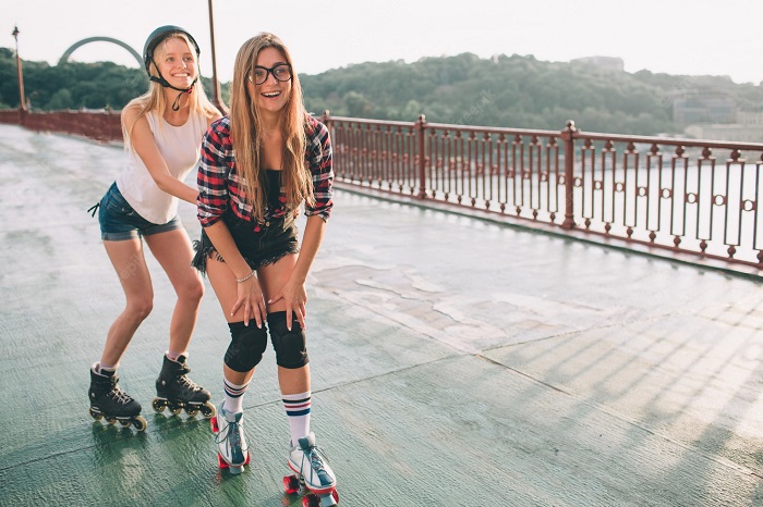 picture of two young girls riding girls quad skates with helmet and knee pads