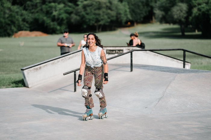 picture of girl riding roller skates in a park with knee pads and wrist guards