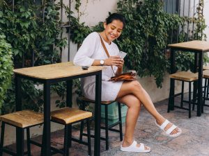 picture of a woman sitting on a high table outside wearing womens dress sandals