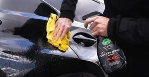 man spraying his car with a cleaning liquid