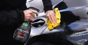 man spraying his car with a cleaning liquid