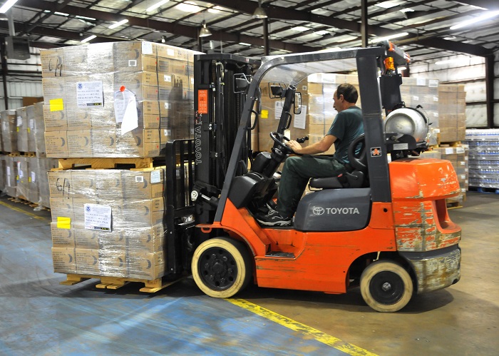 Man driving forklift with load in warehouse
