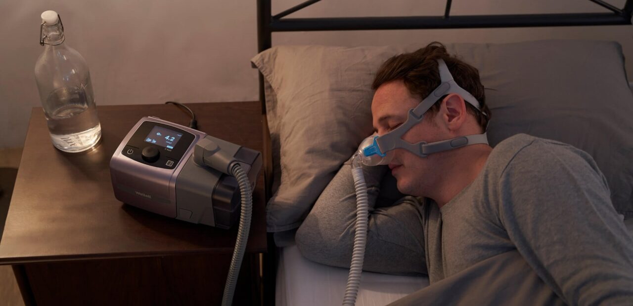 man sleeping while using auto cpap machine