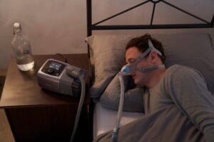 man sleeping while using auto cpap machine