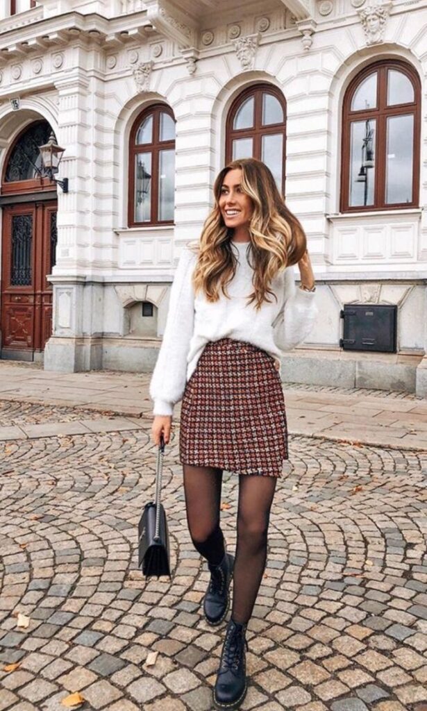 woman wearing white long sleeved top and plaid skirt, black bag and black boots