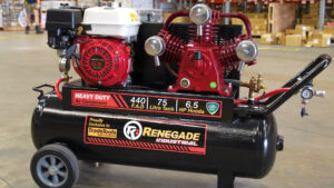 Close-up of a mobile Renegade Industrial air compressor with a large red Honda engine and a black tank, on a warehouse floor.