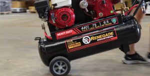 Side view of a Renegade Industrial heavy-duty air compressor with wheels and a red Honda motor, in an industrial setting.