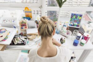 woman on a table with a lot of art and craft materials