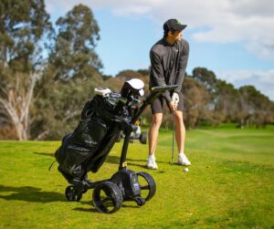 a person playing golf next to a motorised golf buggy