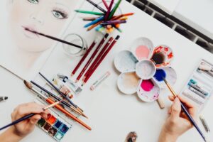 person painting with watercolour paints and pencils